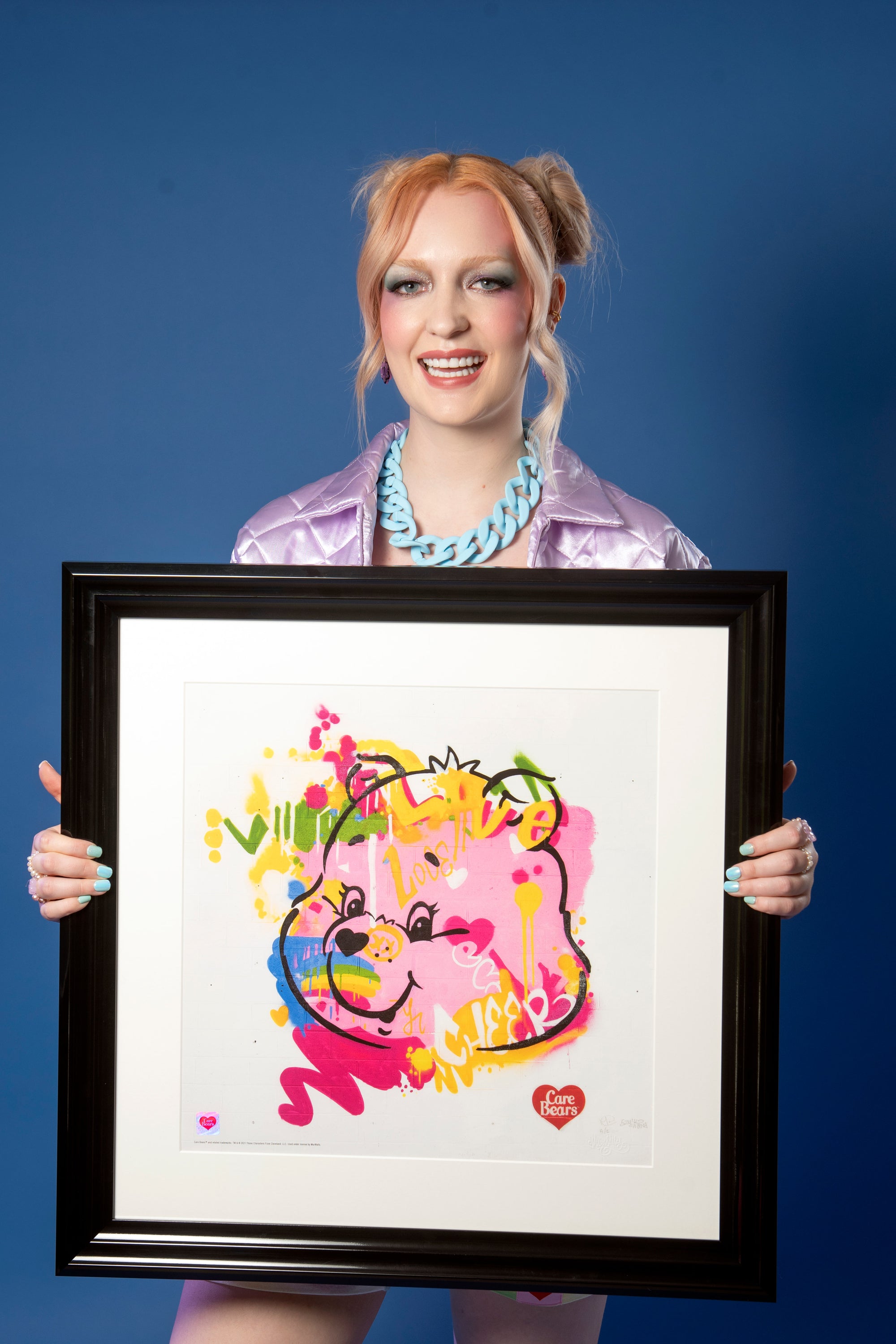 Model holding a framed Care Bears Cheer Bear print by MurWalls