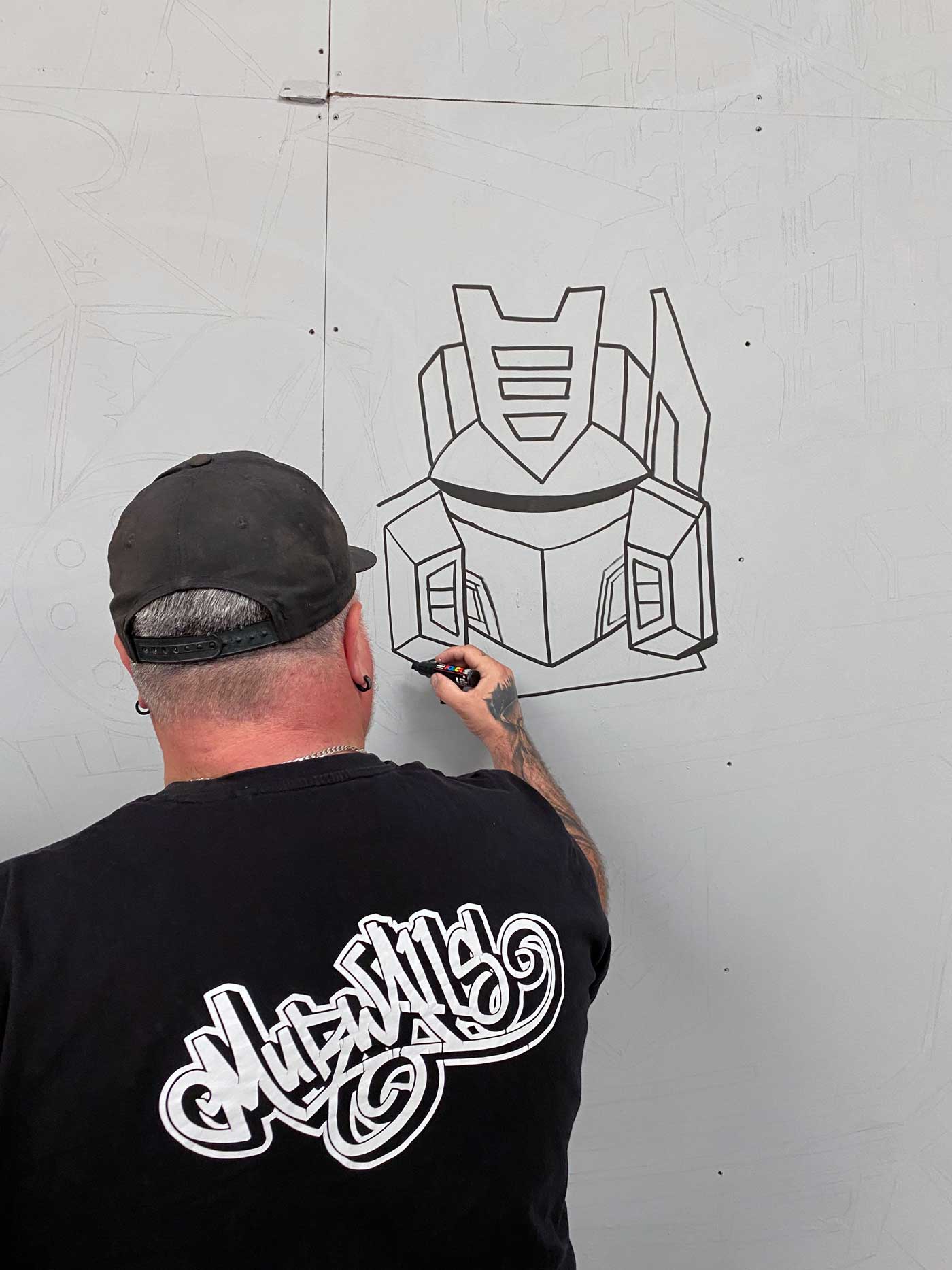 MurWalls artist creating the Megatron and Soundwave mural